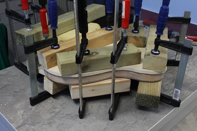 Zdjąłem lakier, następnie u znajomego stolarza zebraliśmy odpowiednią warstwę drewna z grubości (pod top). Squier seryjnie był cieńszy niż podaje Fender, więc przy okazji lekko pogrubiłem korpus co wiązało się z koniecznością wklejenia kawałka drewna w kieszeń gryfu. Ścięcie pod przedramię też zostało zebrane. Przy pomocy nacięć od spodu, wytwornicy pary udało się zakrzywić top pod wspomniany skos pod przedramię. (ale namieszałem). Następnie przykleiłem go i umieściłem w ściskach.